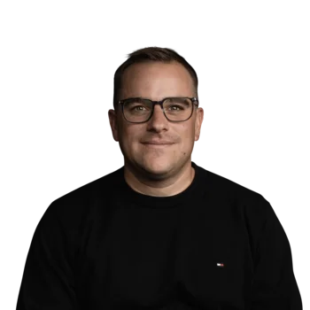 Peter Huber | Head of Product Porträt eines lächelnden Mannes mit schwarzen Brillengläsern und schwarzem Hemd