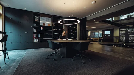 Woman working at a table in a modern stylish office with bookshelves