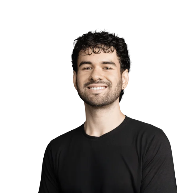 Junger Mann mit lockigem Haar und schwarzem Shirt lächelt freundlich