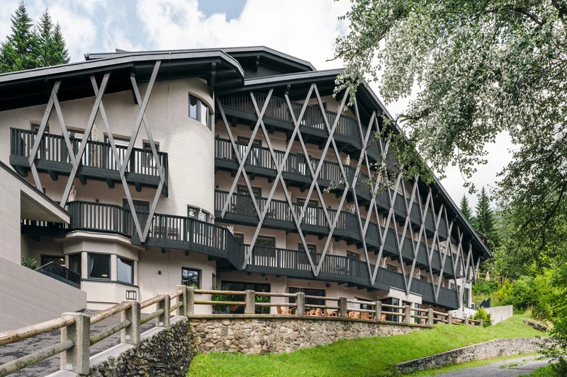 Modernes Hotelgebäude mit Balkonen und Holzzäunen in grüner Umgebung