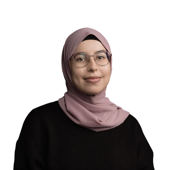 Frau mit rosa Kopftuch und Brille, lächelnd, vor weißem Hintergrund